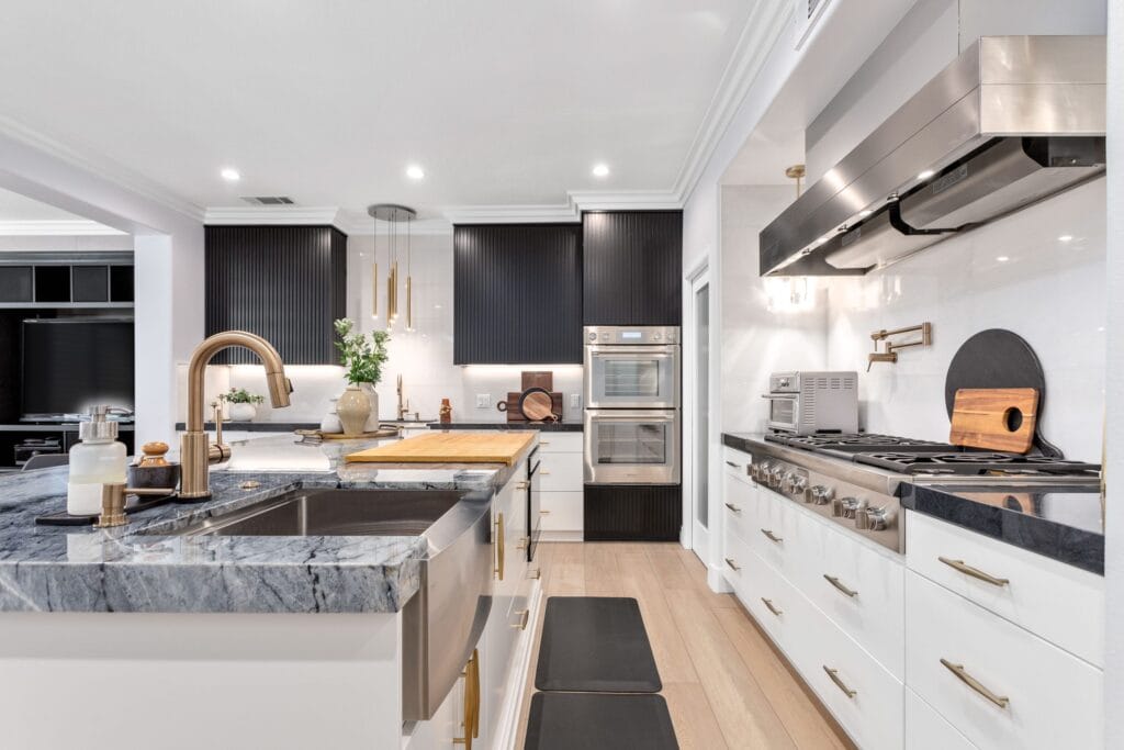 The cooking run with a brass tap, built-in ovens and the range, seen across the island worktop