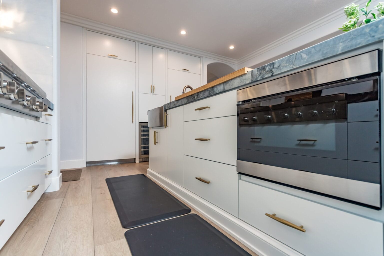 Base cabinetry and a built-in oven beneath a dark stone shelf, with the pale timber floor running through
