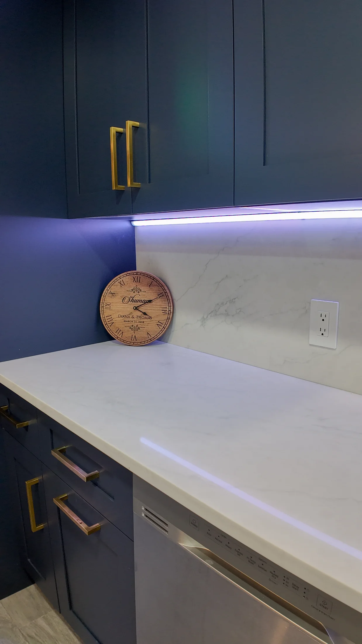 Close view of a navy cabinet door with a brass bar pull and quartz worktop edge
