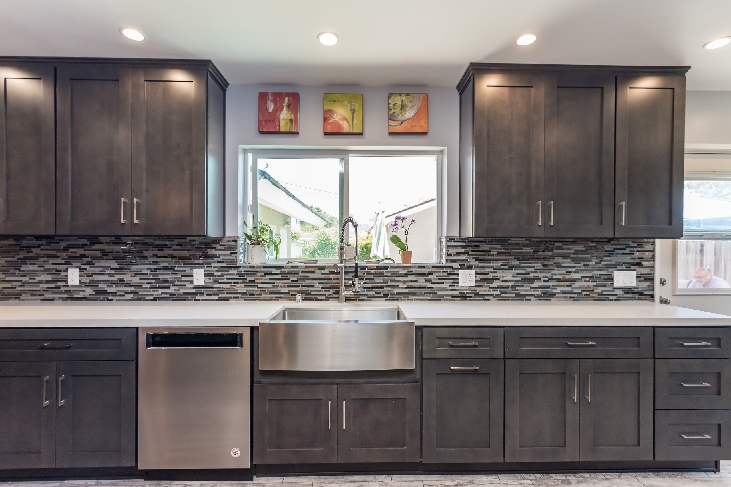 Kitchen sink run with an apron-front sink and integrated dishwasher under a window, splashback complete
