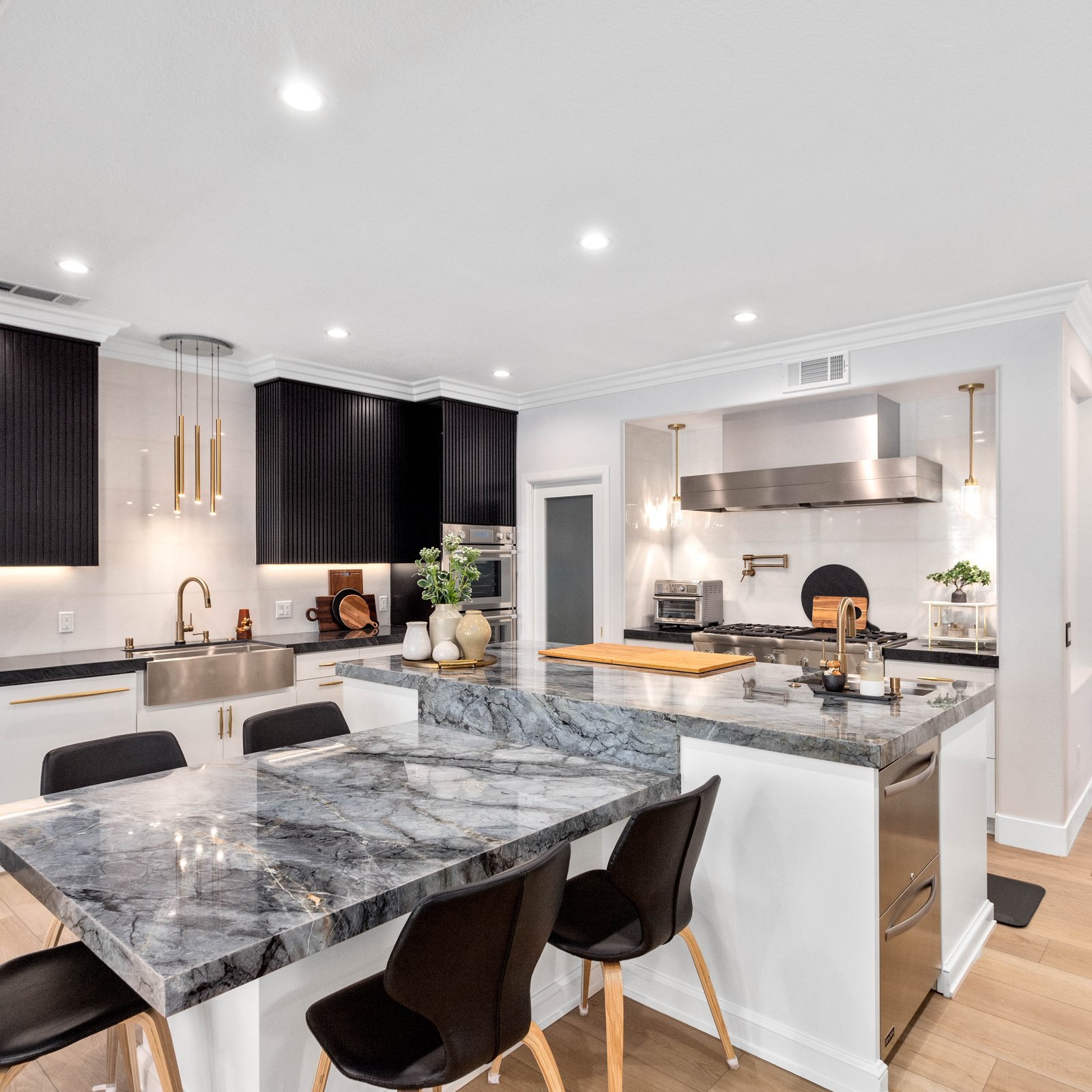 Open kitchen with black fluted cabinetry, marble island and pendant lighting