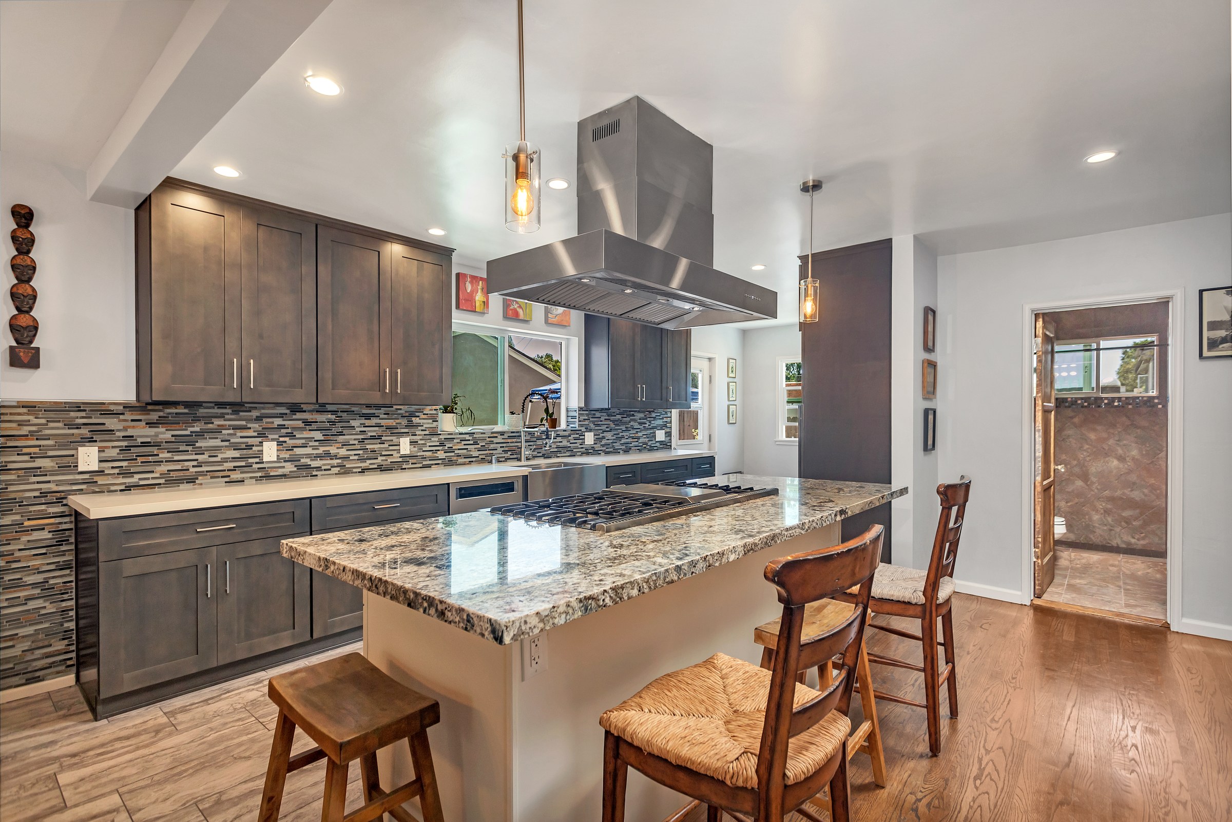Kitchen remodel with a granite island, professional gas range, island hood and mosaic tile backsplash