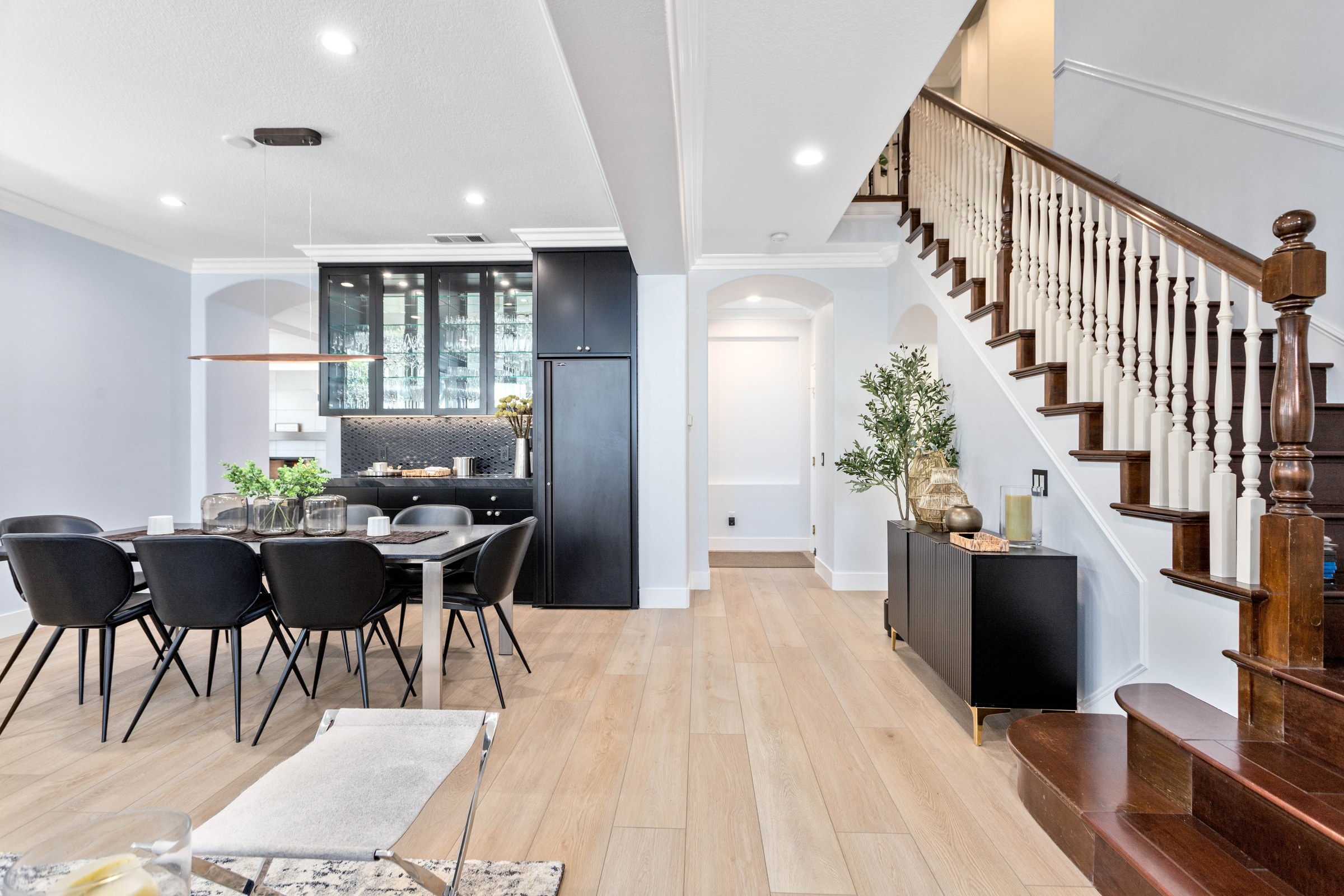 Open-plan dining and kitchen after a whole-home renovation, with wide-plank floors and a restored staircase