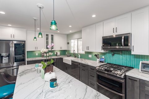 Kitchen remodel with teal herringbone tile, marble counters and glass pendants