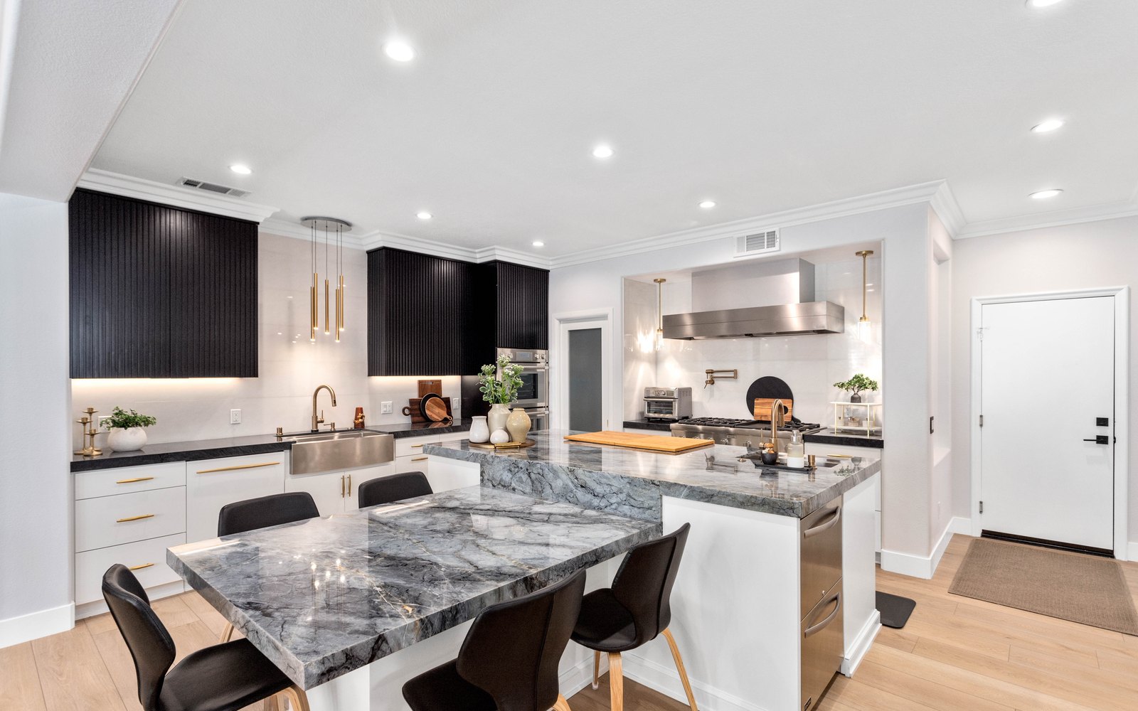 Open kitchen with black fluted cabinetry, marble island and pendant lighting