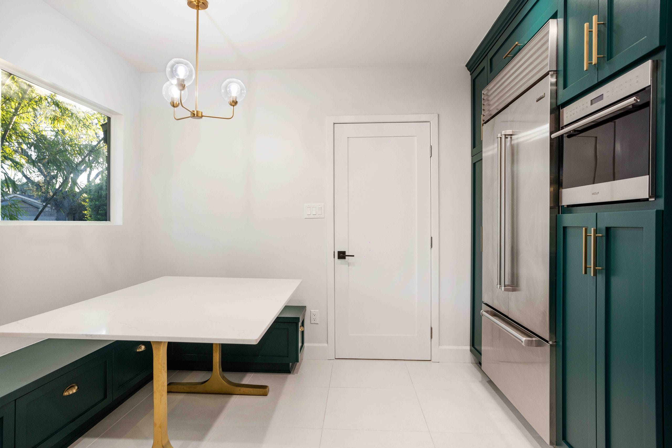 The quartz table and its bench seat under the chandelier, tall cabinetry beyond