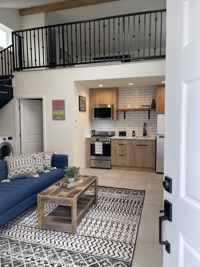 A larger two-storey ADU by Elbaz Construction with a loft bedroom, full kitchen and laundry, shown for scale against a studio unit