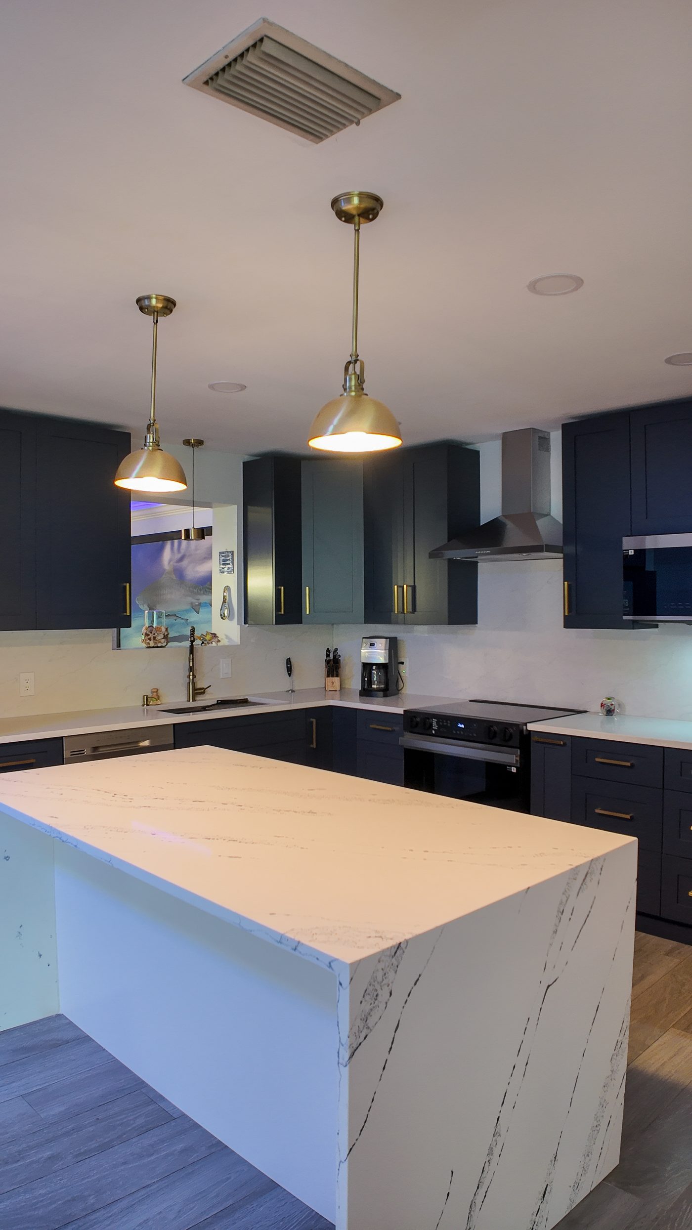 Brass pendants hung over the quartz island in a completed kitchen remodel