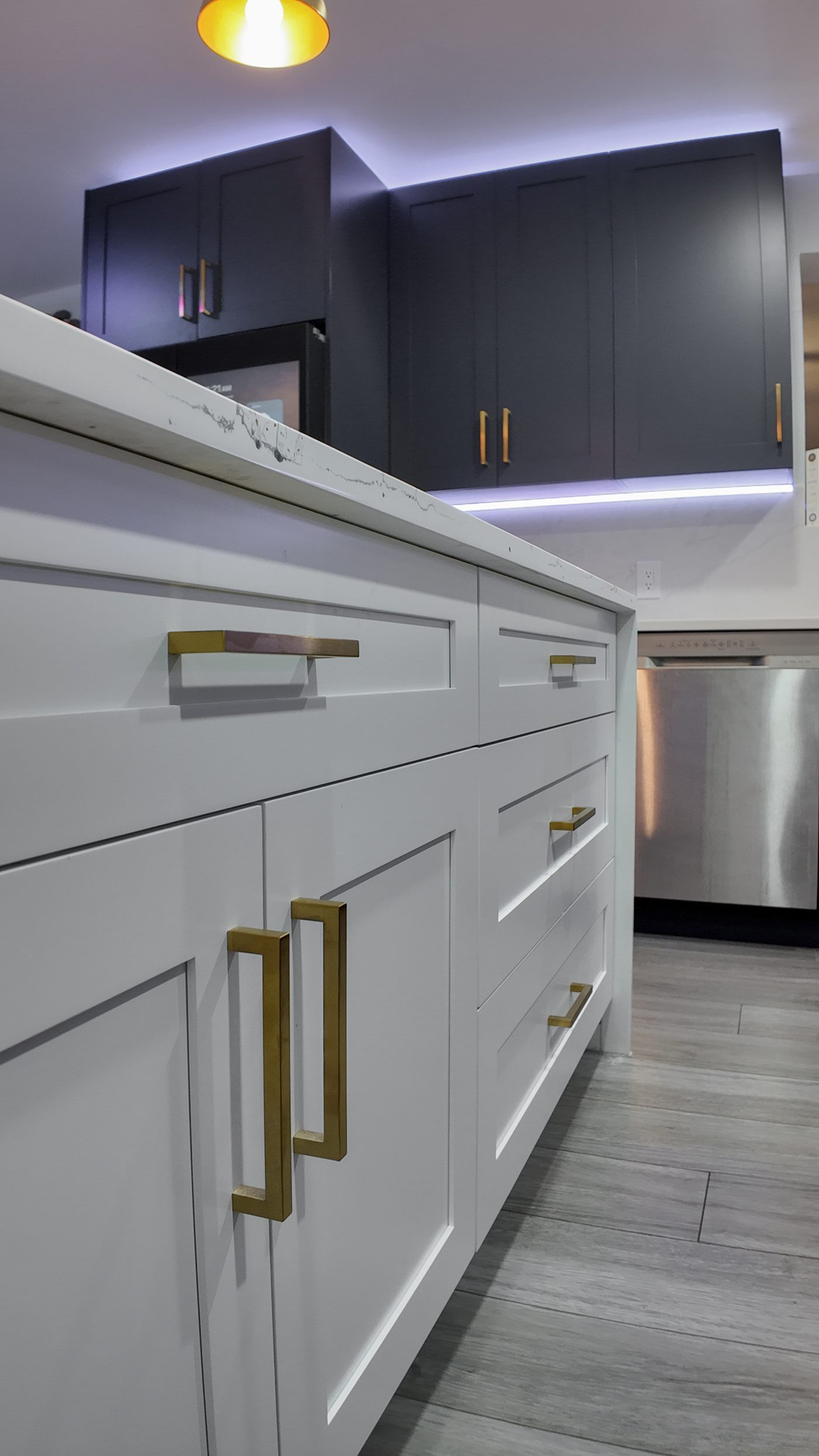 White island drawer bank with brass pulls beside an integrated dishwasher