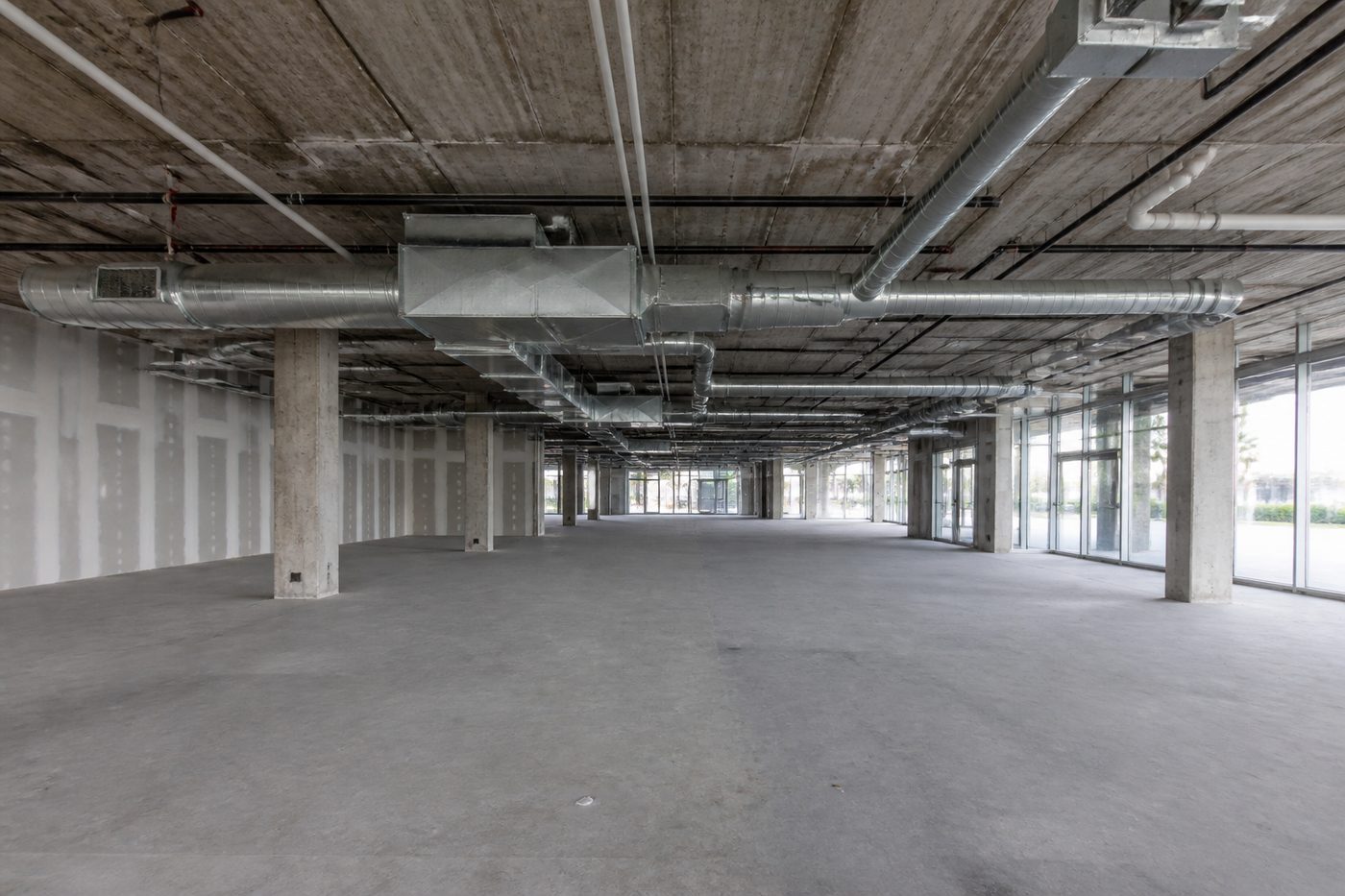 AI-generated illustration: an empty commercial shell space before fit-out, with exposed structure and services overhead