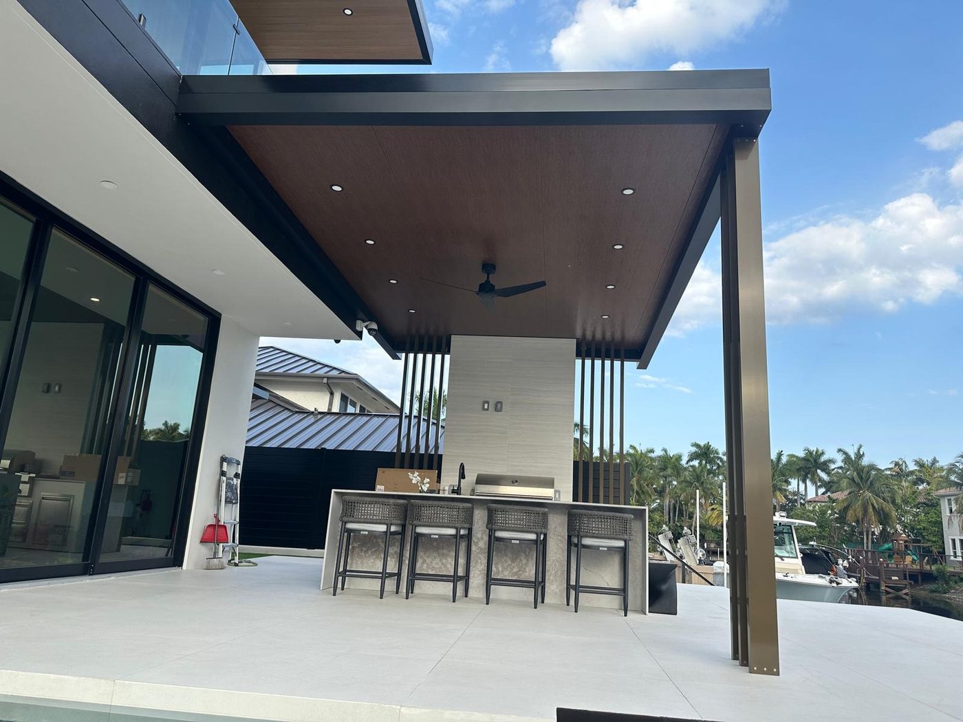 Bar seating at a counter under a cantilevered cover, water beyond