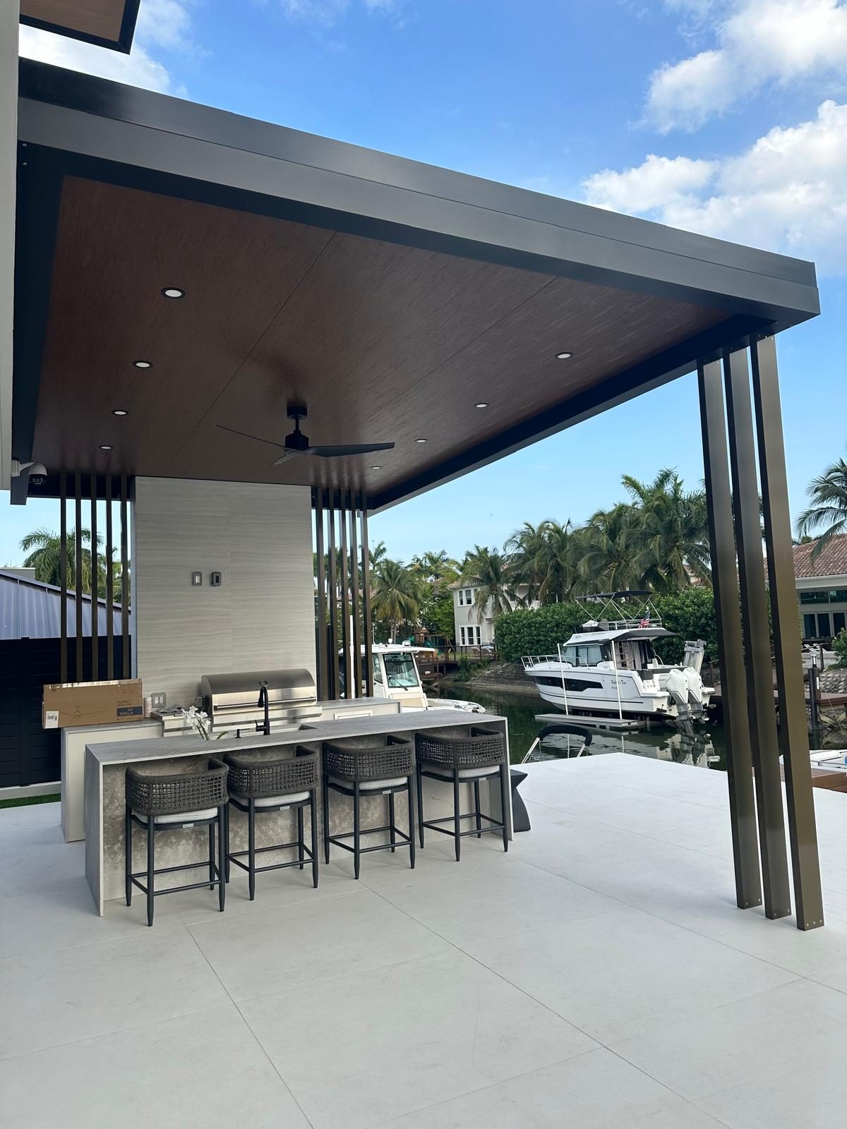 Built-in outdoor kitchen with bar stools, boats moored beyond