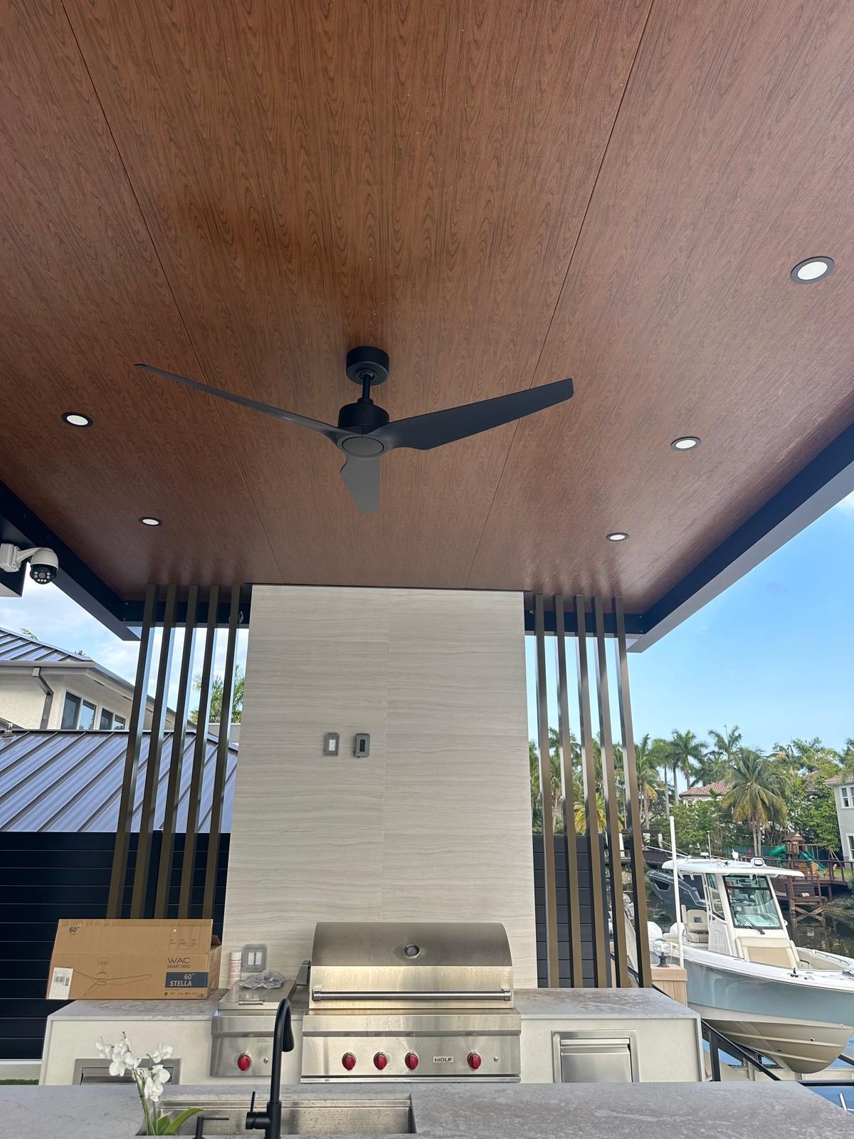 Built-in grill and burner run under a timber-clad soffit with a ceiling fan