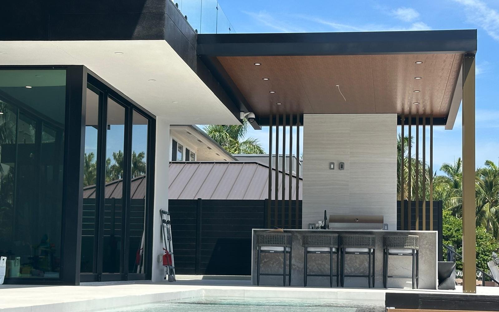 Covered outdoor kitchen and pergola with pool overlooking a South Florida waterway