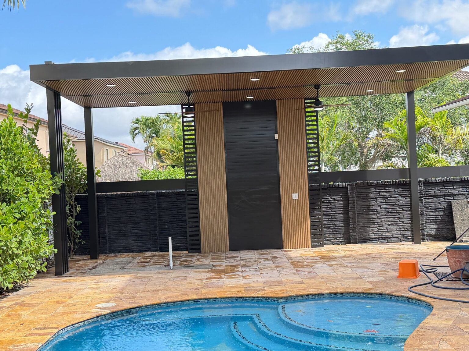 The pool and deck from the opposite corner, with the cabana and screened boundary wall behind
