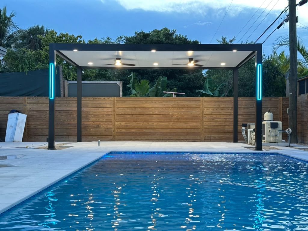 Pool and dark pergola photographed at dusk against a horizontal timber fence, with the structure lit from within, by Elbaz Construction
