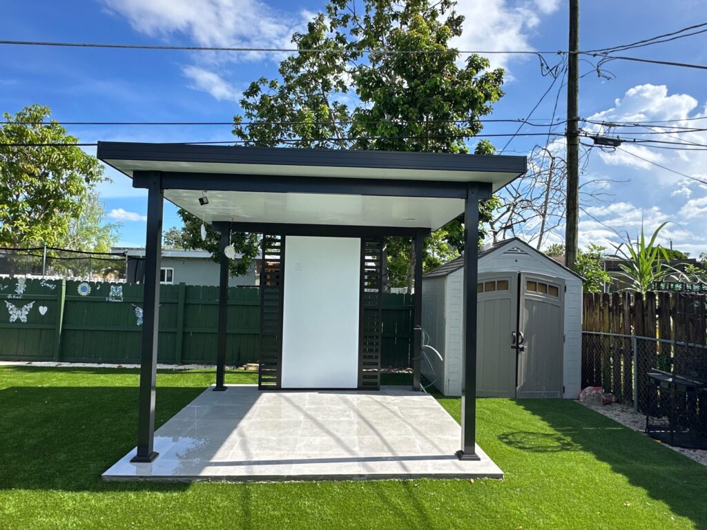 The same cabana seen along the boundary, between a timber fence and a garden store