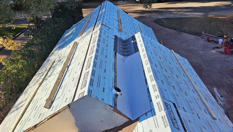 Roof mid-replacement with underlayment down and barrel tile being loaded out