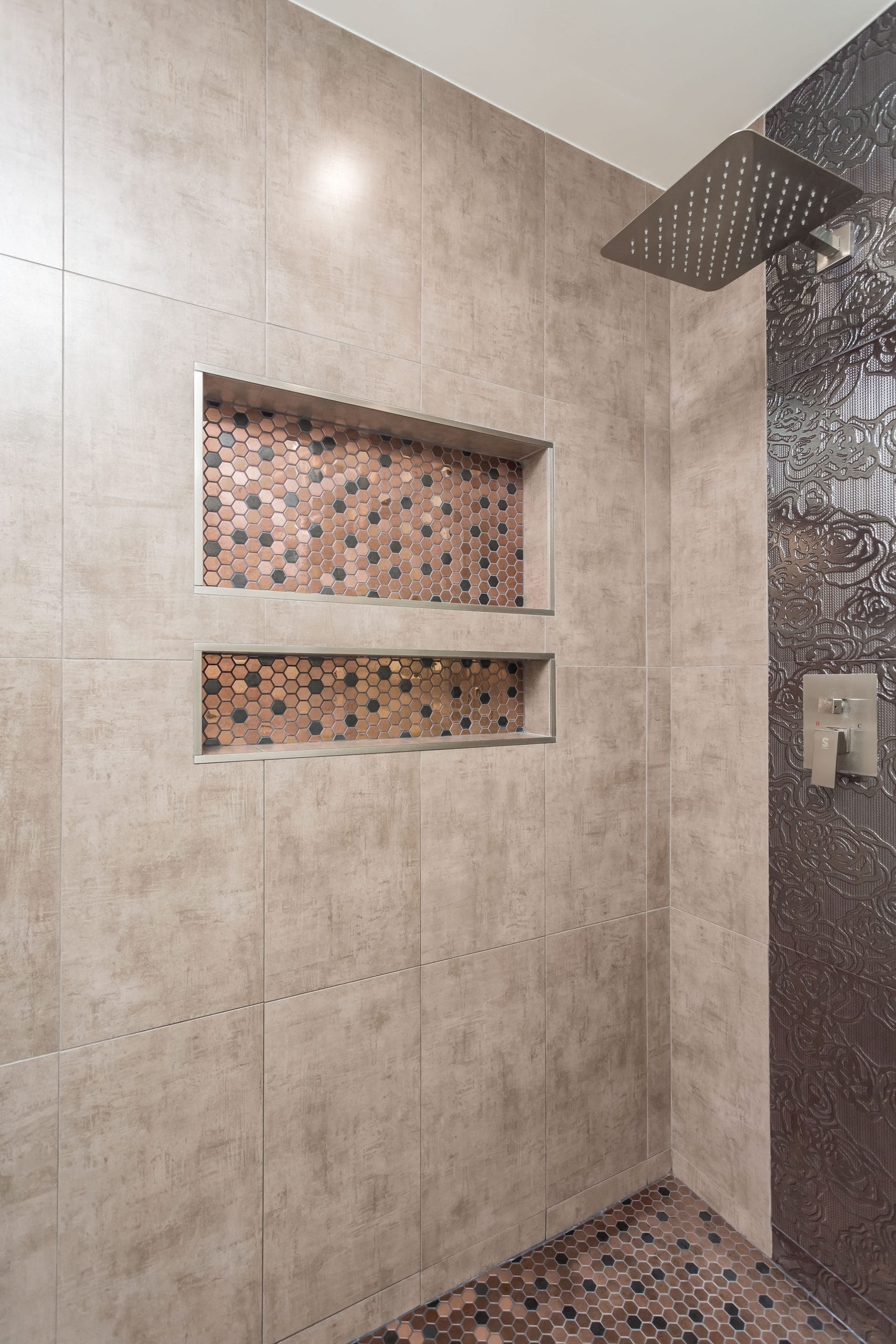 The rain head and the mosaic band running the full height of the shower wall