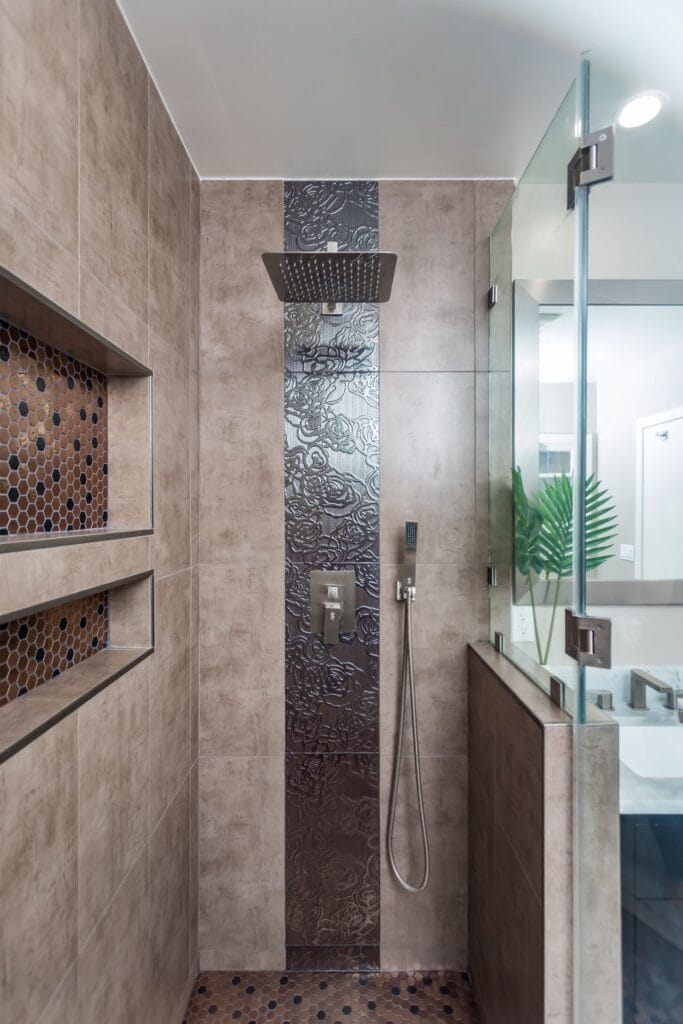 Compact bathroom remodel by Elbaz Construction with a walk-in shower, copper-tone penny mosaic niches and floor, textured feature tile and a dark vanity with a stone top