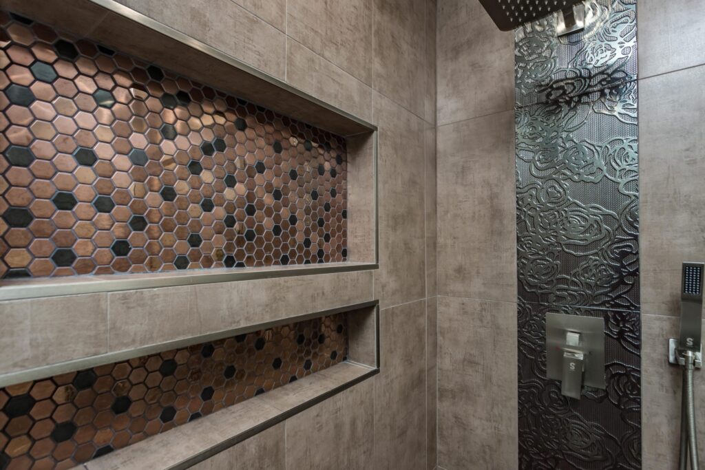 Compact bathroom remodel by Elbaz Construction with a walk-in shower, copper-tone penny mosaic niches and floor, textured feature tile and a dark vanity with a stone top