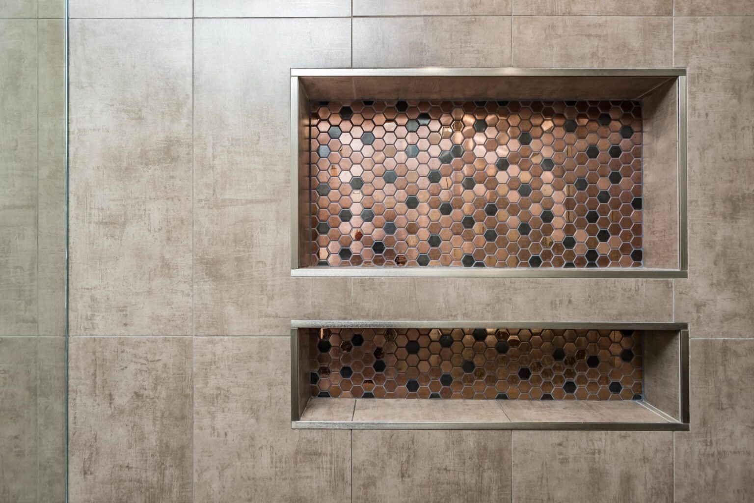 Two recessed niches formed in the tiled wall and lined with copper-toned penny mosaic