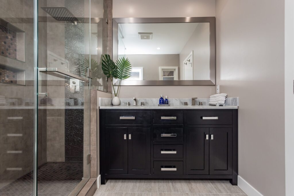 Compact bathroom remodel by Elbaz Construction with a walk-in shower, copper-tone penny mosaic niches and floor, textured feature tile and a dark vanity with a stone top
