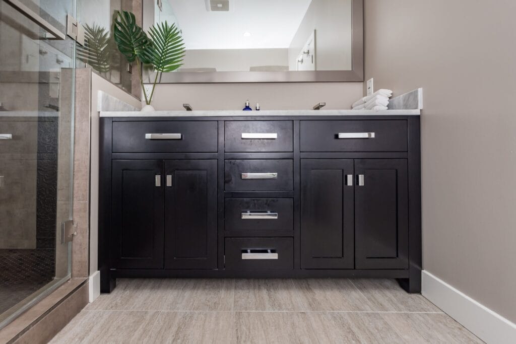 Compact bathroom remodel by Elbaz Construction with a walk-in shower, copper-tone penny mosaic niches and floor, textured feature tile and a dark vanity with a stone top