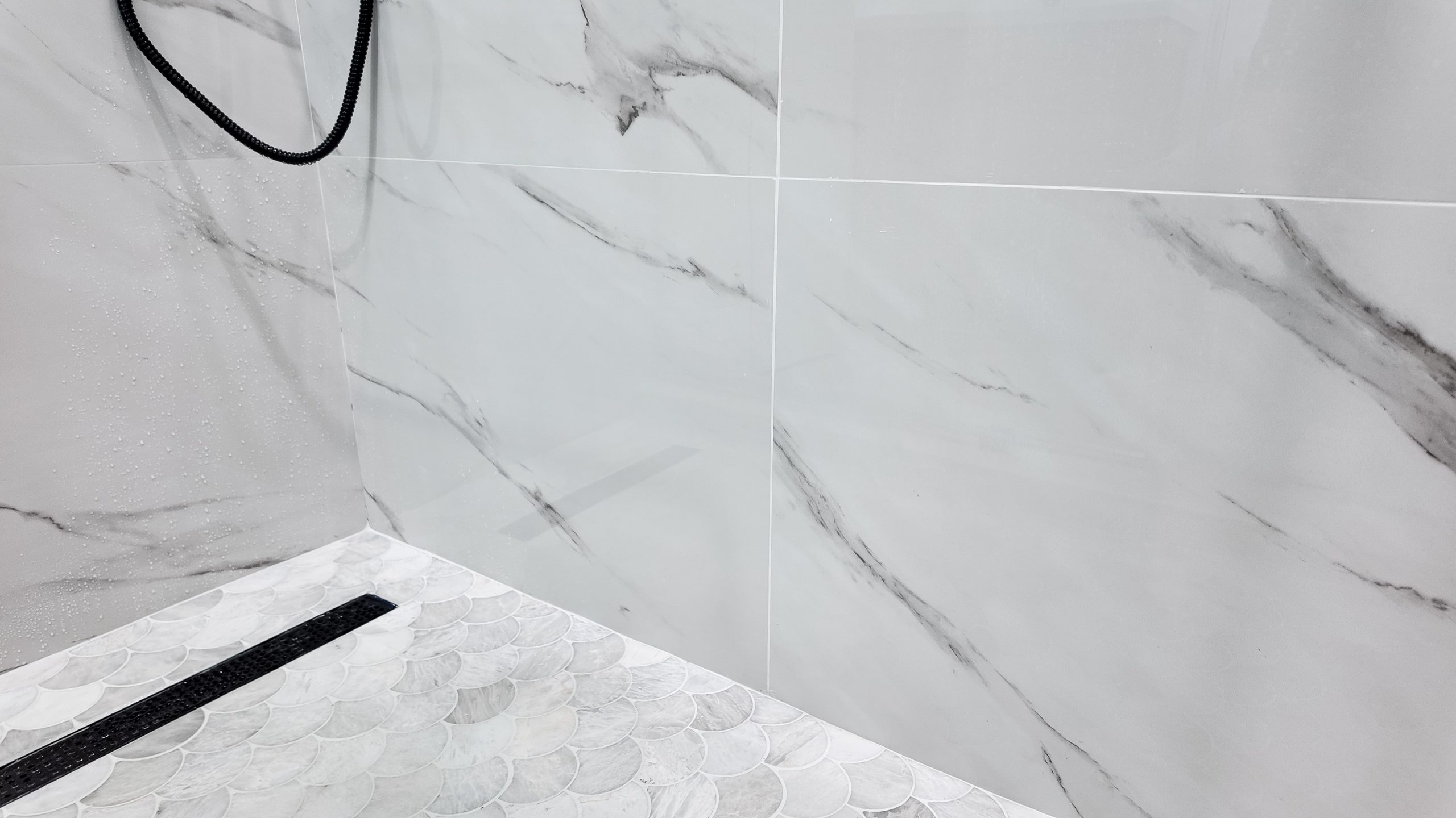 Where the shower wall tile meets the floor: the linear drain channel and the fall built into the pan before tiling