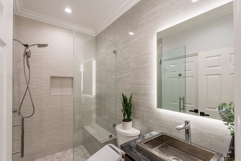 Narrow bathroom remodel by Elbaz Construction with textured wave-pattern wall tile, a walk-in shower with bench and niche, a backlit mirror and a floating vanity