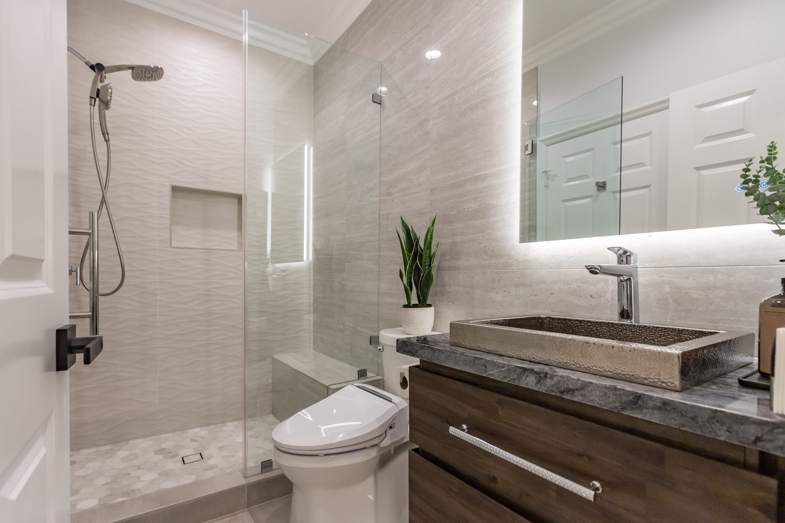 Floating timber vanity with a carved stone basin, black tap and the WC alongside