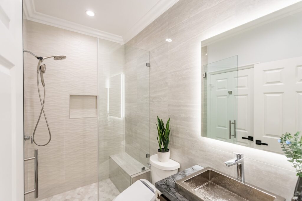 Narrow bathroom remodel by Elbaz Construction with textured wave-pattern wall tile, a walk-in shower with bench and niche, a backlit mirror and a floating vanity
