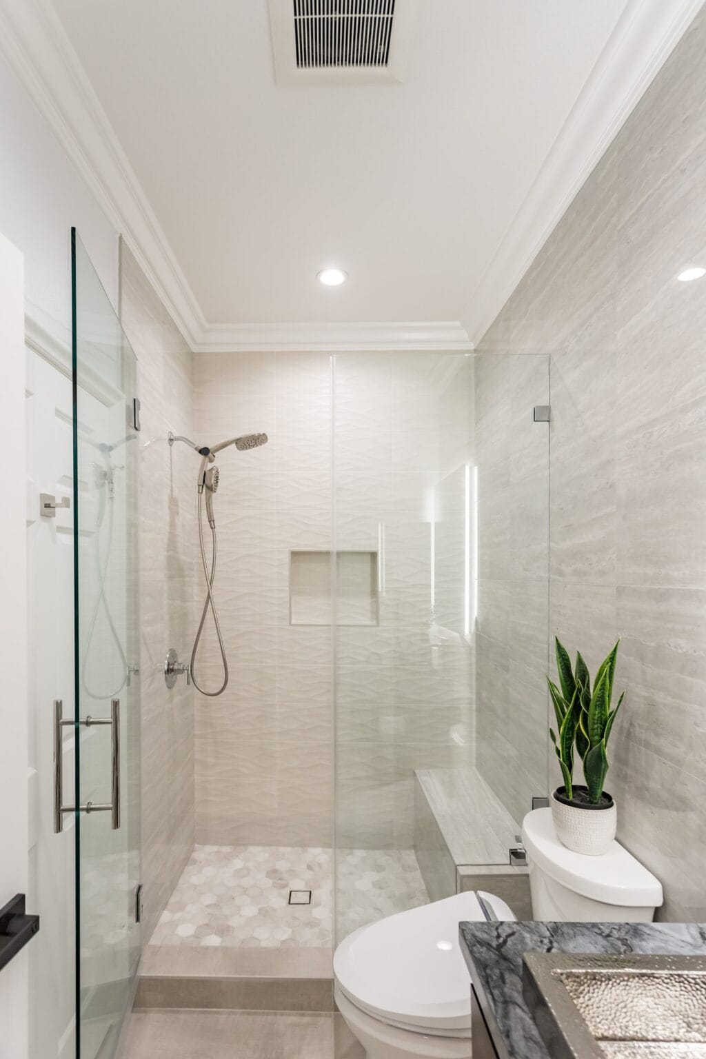 The same bathroom looking into the shower, with the wave-textured wall tile and the recessed niche
