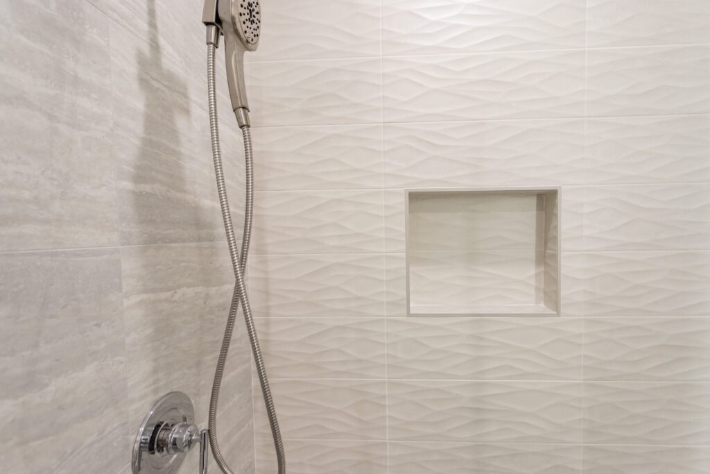 Narrow bathroom remodel by Elbaz Construction with textured wave-pattern wall tile, a walk-in shower with bench and niche, a backlit mirror and a floating vanity