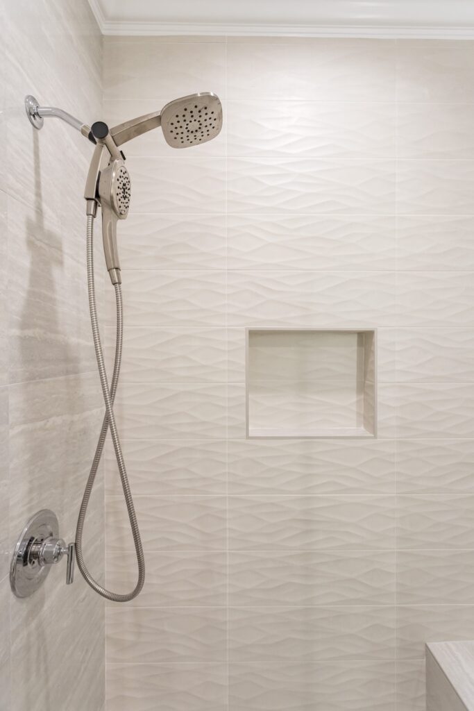 Narrow bathroom remodel by Elbaz Construction with textured wave-pattern wall tile, a walk-in shower with bench and niche, a backlit mirror and a floating vanity