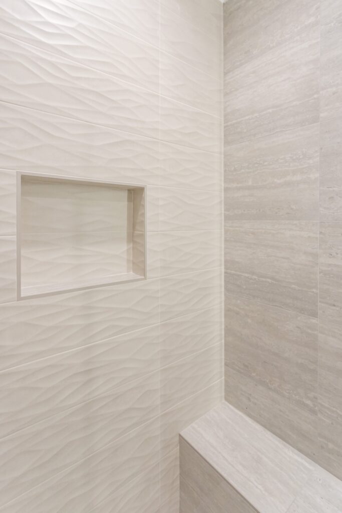 Narrow bathroom remodel by Elbaz Construction with textured wave-pattern wall tile, a walk-in shower with bench and niche, a backlit mirror and a floating vanity