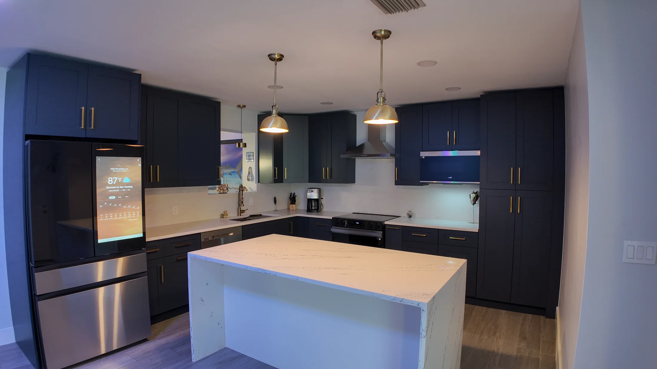 Compact remodelled kitchen with navy cabinetry, a white quartz peninsula and stainless appliances