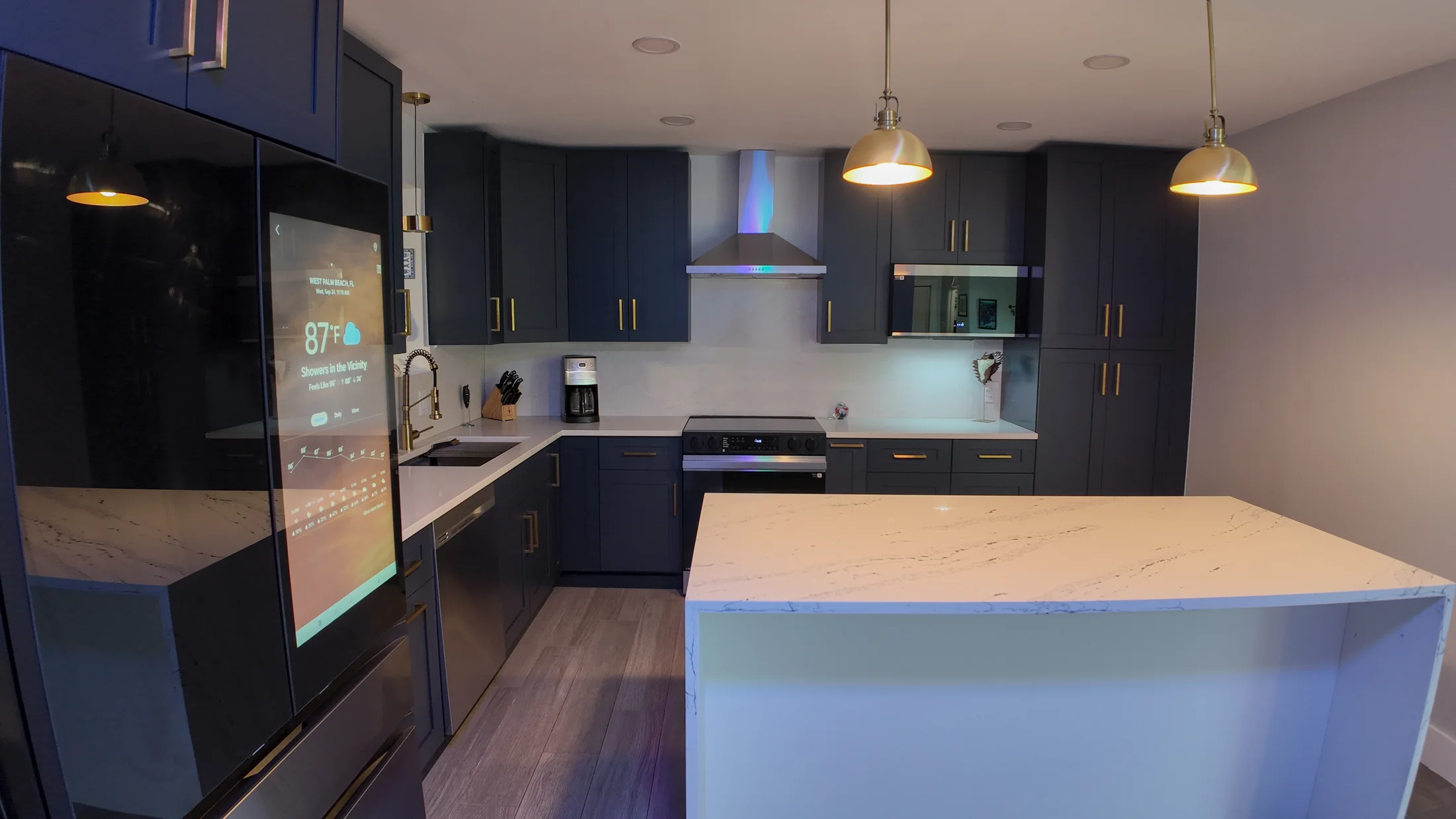 Quartz peninsula with a waterfall end panel beside the navy base cabinet run