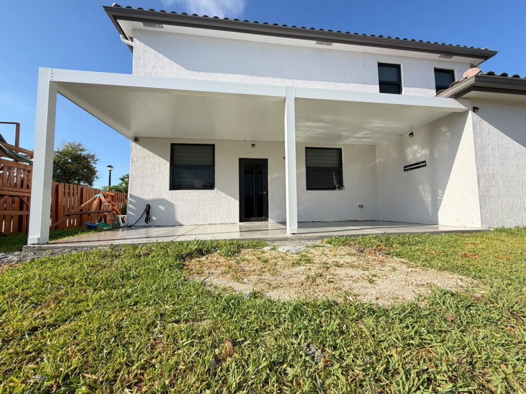 Rear elevation of a two-storey house with a white-framed cover built and the ground not yet made good