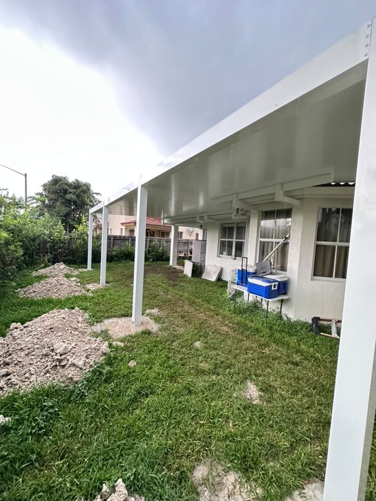 White-framed patio cover part way through construction, with the spoil from the footings still on the grass