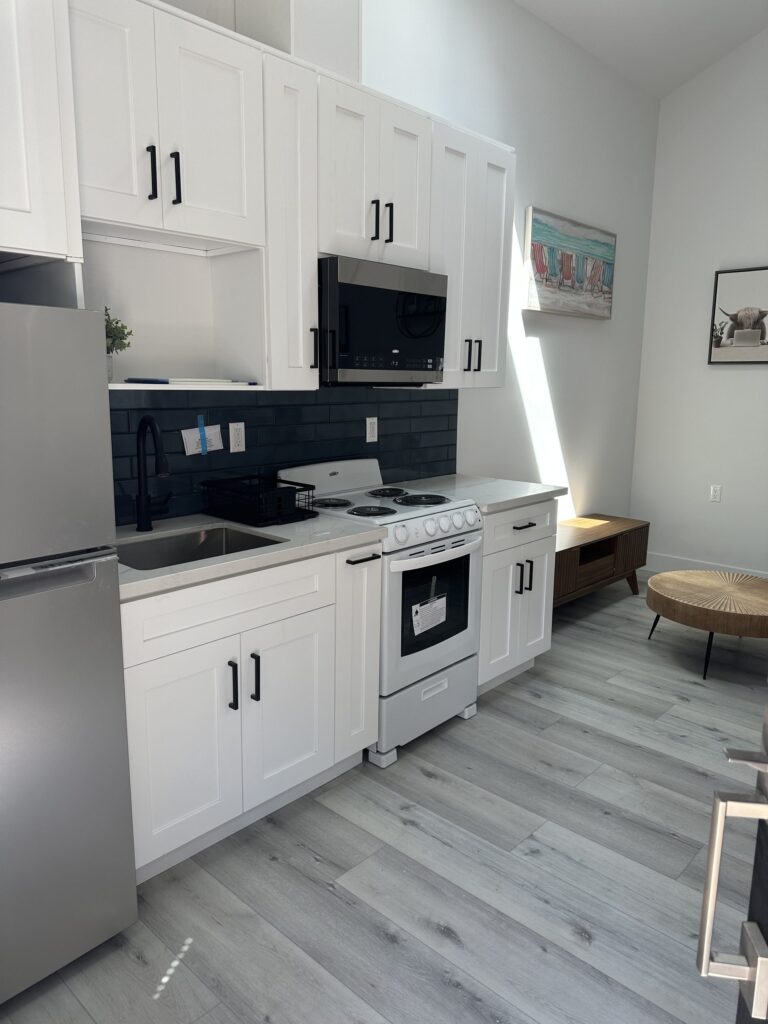 Completed studio ADU by Elbaz Construction: one open room with kitchenette, living and sleeping areas under a vaulted ceiling, plus a compact shower room