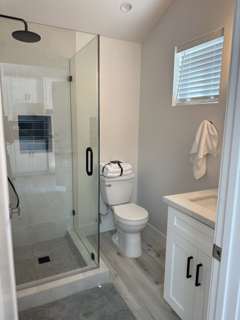 Completed studio ADU by Elbaz Construction: one open room with kitchenette, living and sleeping areas under a vaulted ceiling, plus a compact shower room