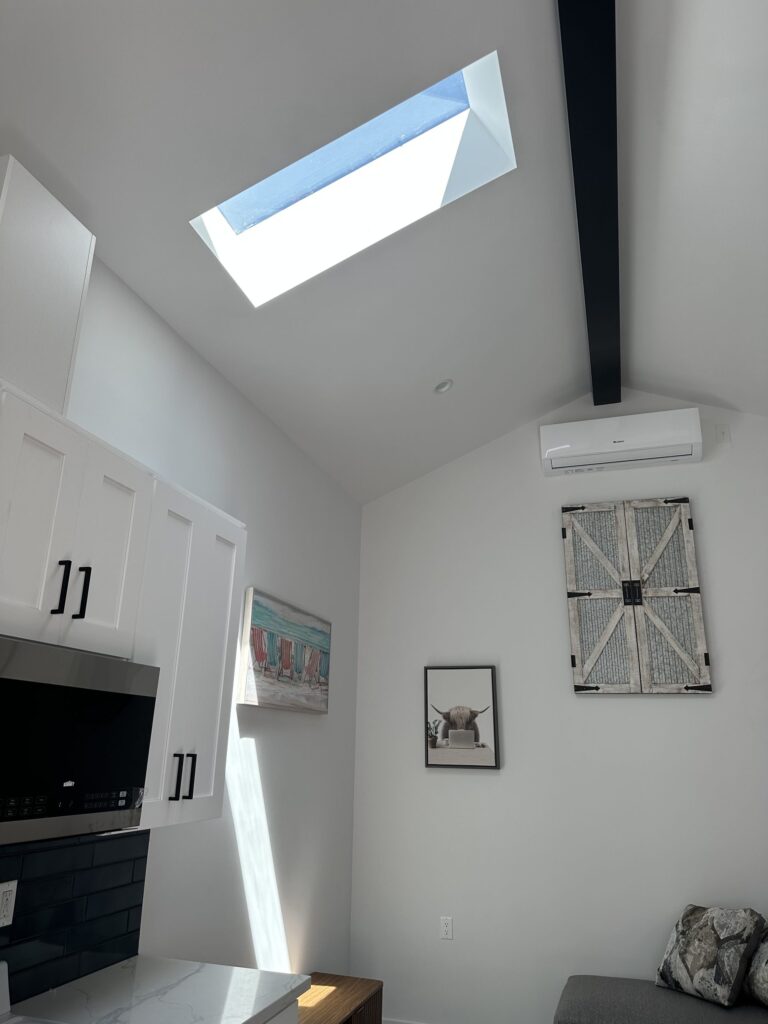 Completed studio ADU by Elbaz Construction: one open room with kitchenette, living and sleeping areas under a vaulted ceiling, plus a compact shower room