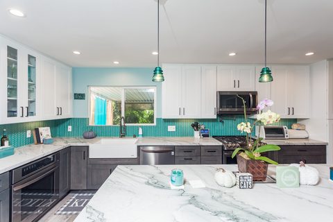 Kitchen with teal herringbone backsplash, farmhouse sink and marble island