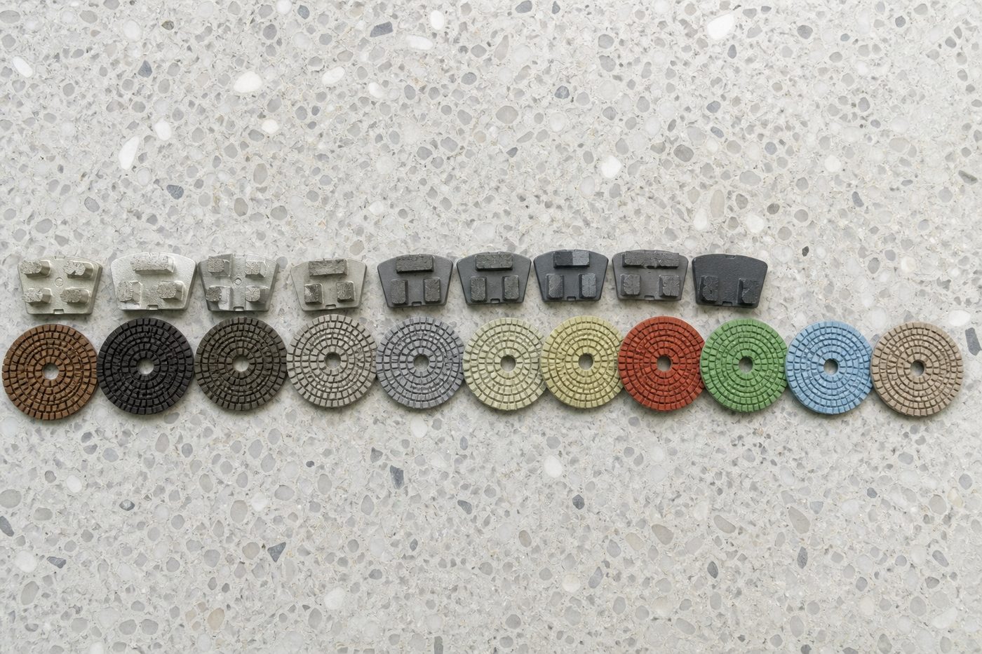 AI-generated illustration: diamond grinding segments and resin polishing pads laid out in grit sequence, coarse to fine