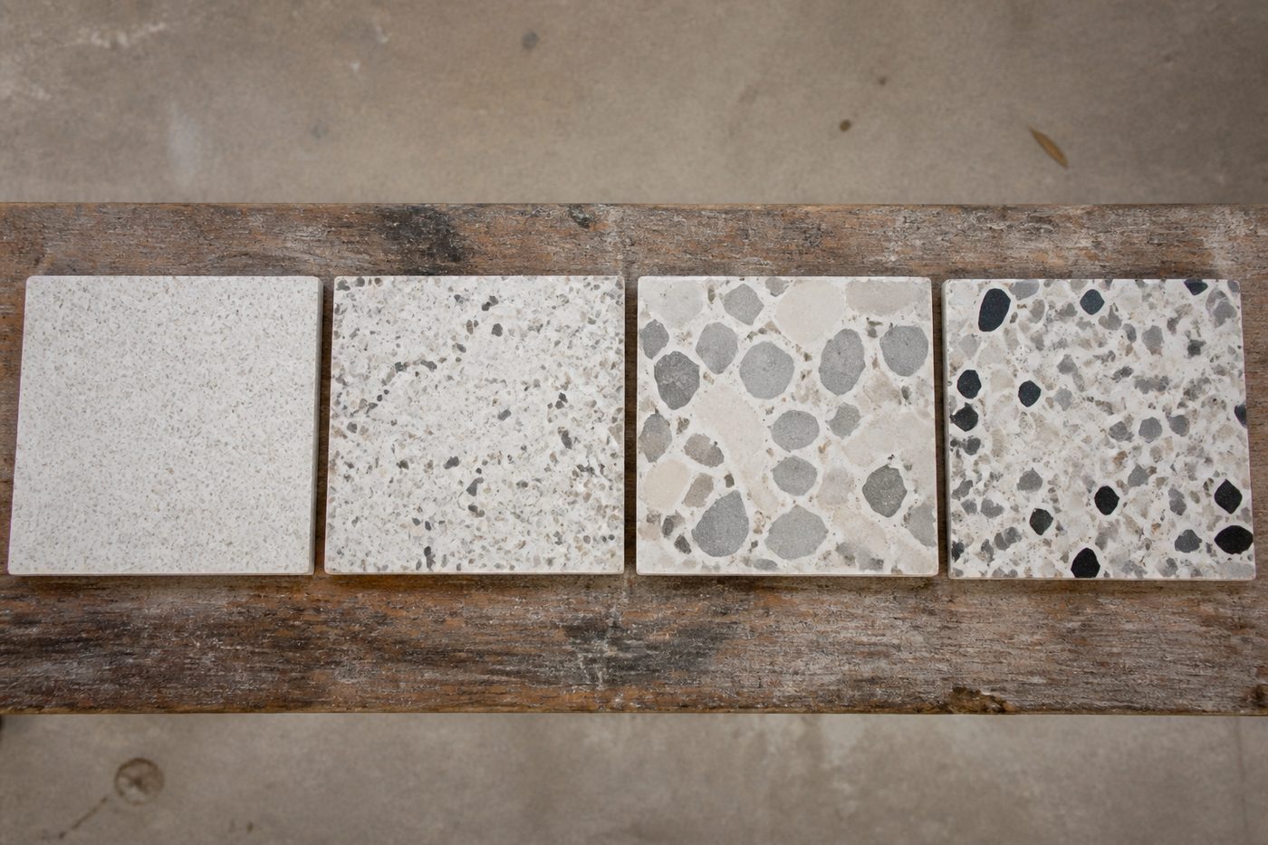 AI-generated illustration: four terrazzo samples side by side showing fine, medium, large and mixed aggregate grades