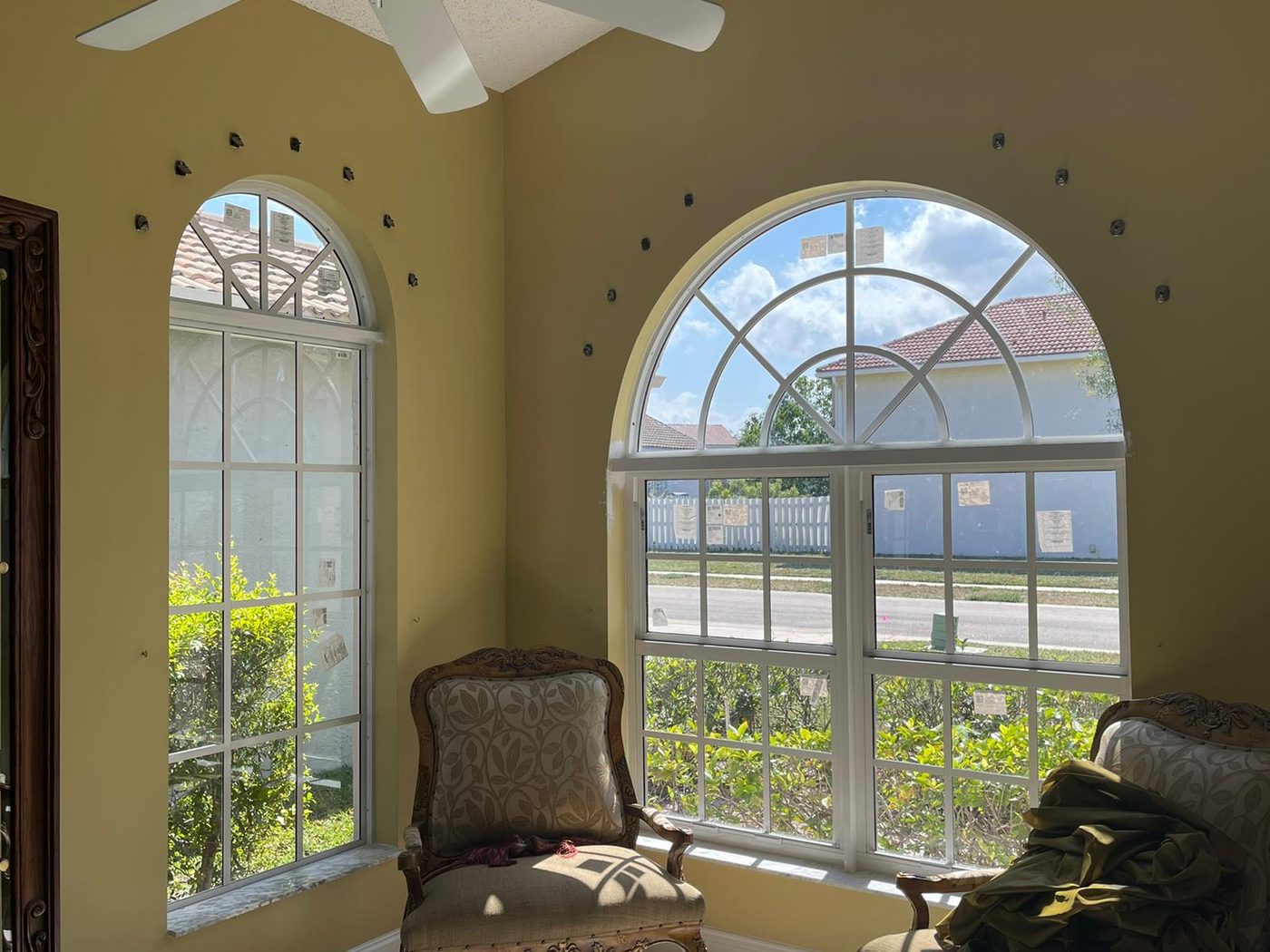 Newly installed arched impact windows with manufacturer labels still on the glass in a South Florida home