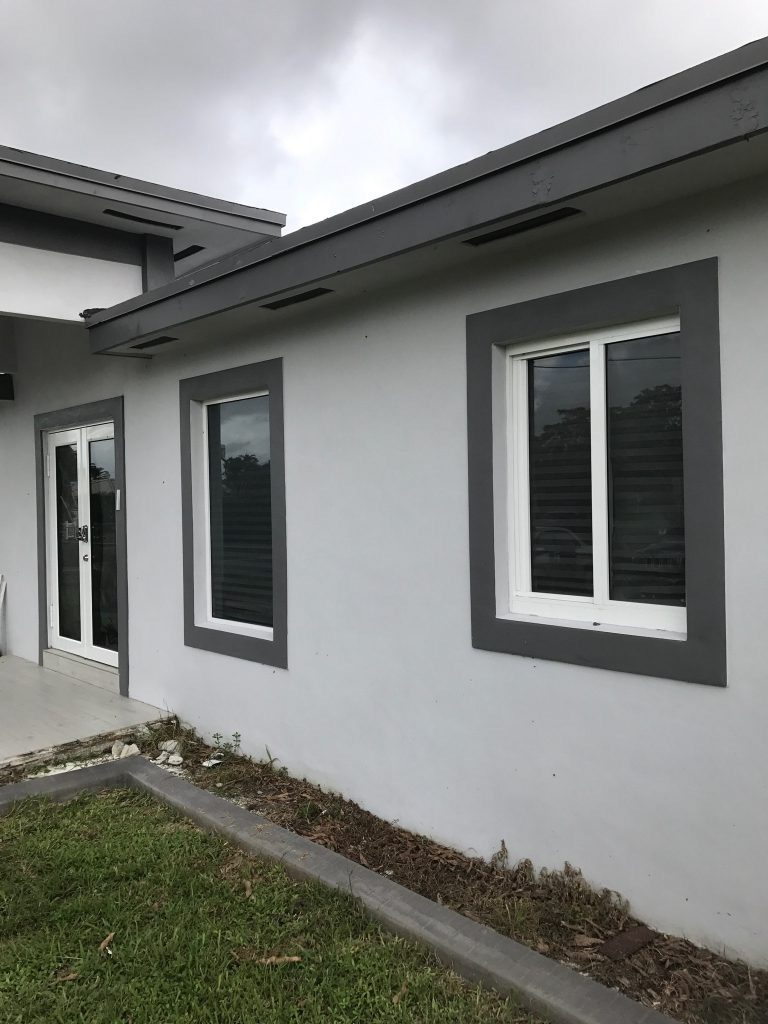 Two replacement windows with dark frames set into a rendered wall