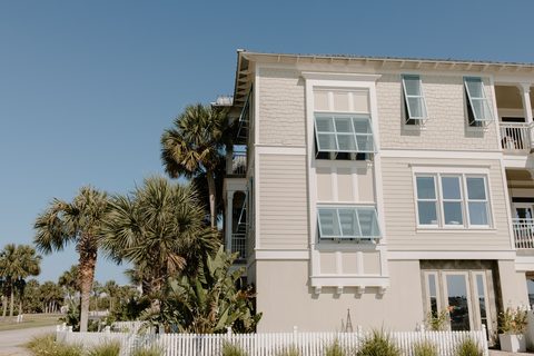 Coastal home with Bahama-style storm shutters above impact-rated windows