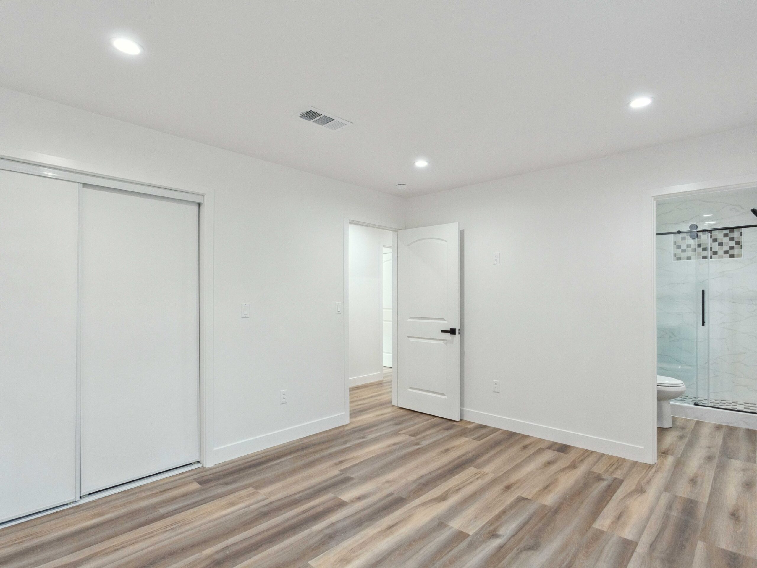 Sleeping area in the converted garage with an egress window and plank flooring